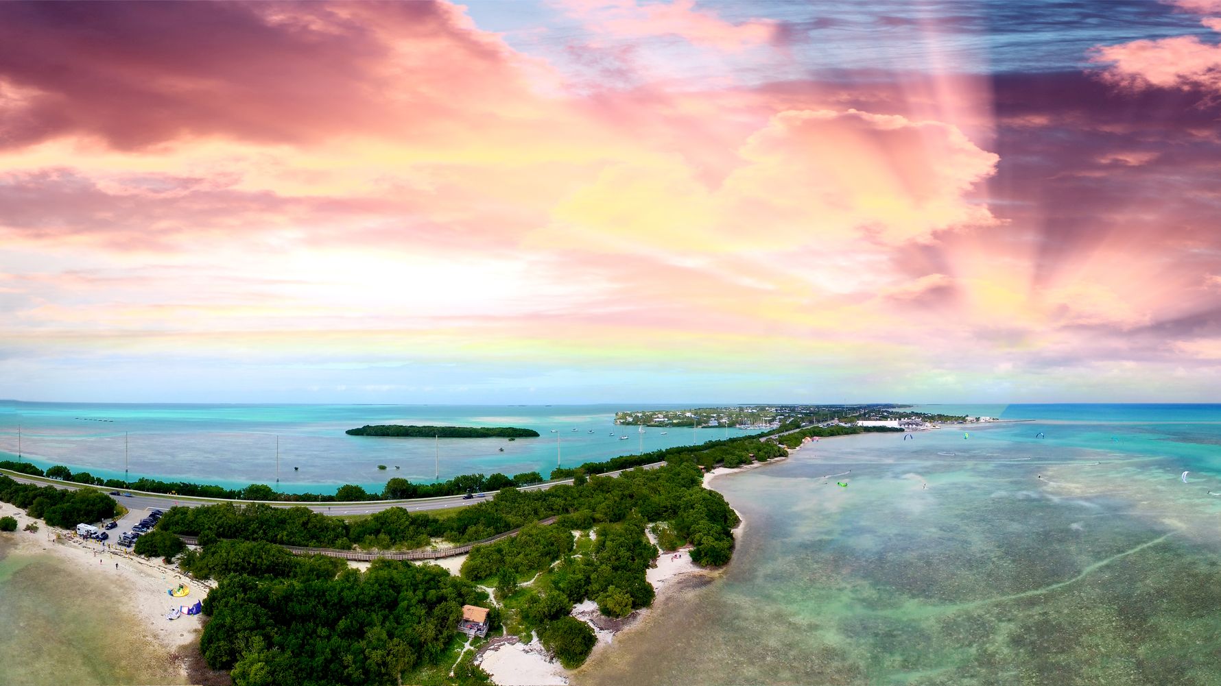 A stunning aerial view of a tropical island with lush greenery, surrounded by turquoise waters and a vibrant sunset painting the sky in shades of pink and orange.