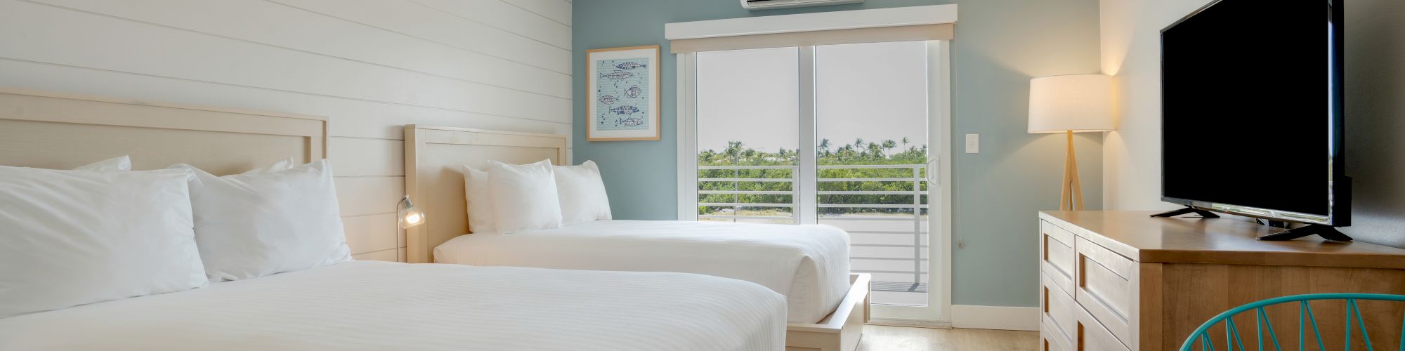 A modern hotel room with two beds, a TV, wooden furniture, and a balcony with a view. Minimalist decor and a mix of white and blue tones end the sentence.