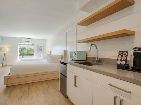 Bright studio room with a bed, kitchenette, and a coffee machine.