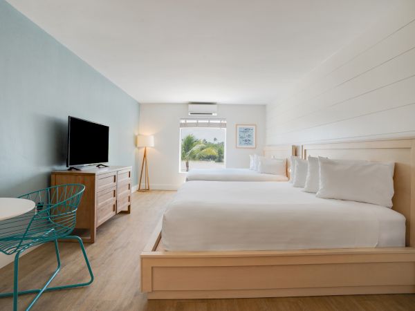 A neat, modern hotel room with a large bed, TV, console, and