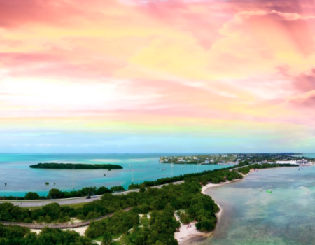 A stunning aerial view of a coastal area with vibrant turquoise waters and a colorful sky at sunset.