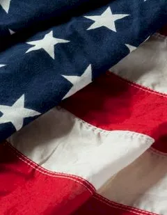 Close-up of a US flag fabric, showing navy stars and red-and-white stripes.